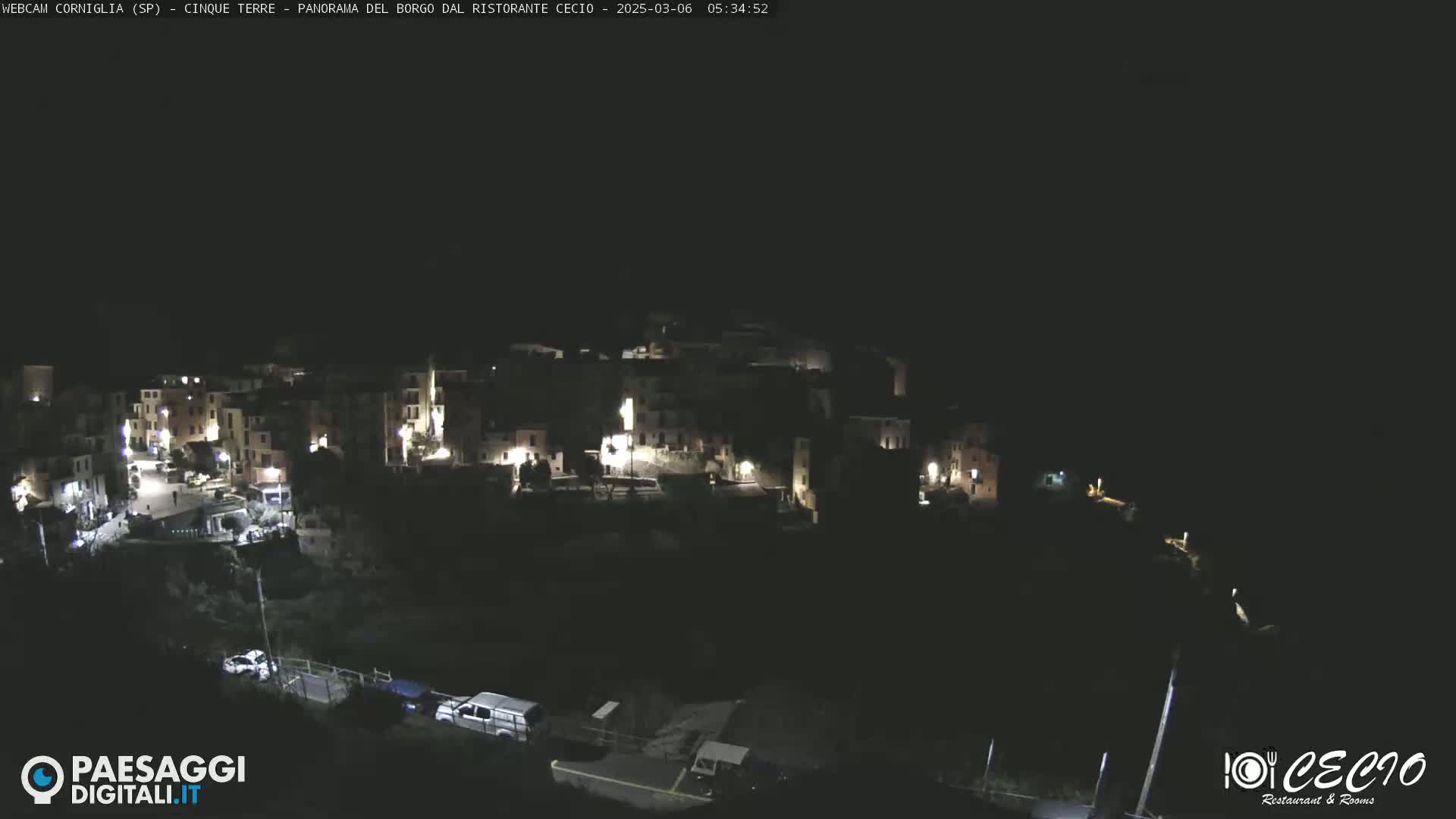 A nighttime, high-angle view of a small, illuminated town nestled into a dark hillside.