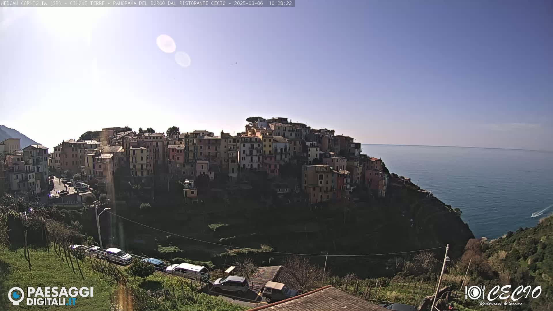 A sunny day shows a coastal town built on a hillside overlooking a calm sea.