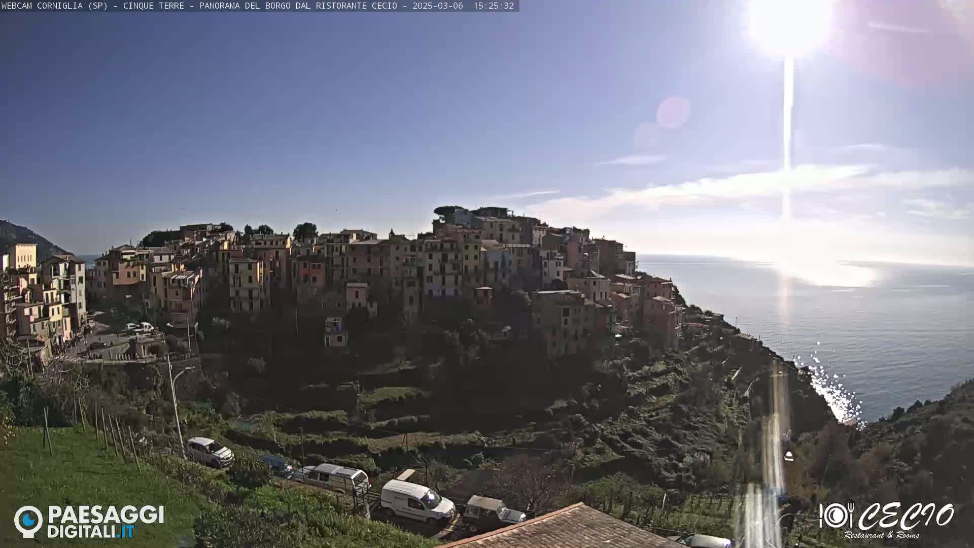 A sunny day overlooks a colorful hillside village perched on a cliff overlooking the ocean.