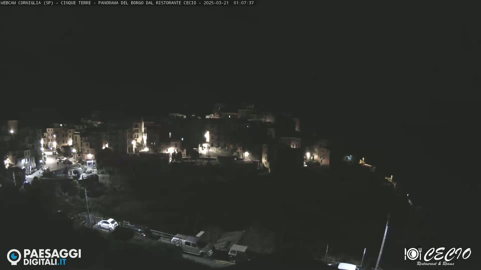 A nighttime, overhead view of a small, dimly lit town nestled into a hillside.