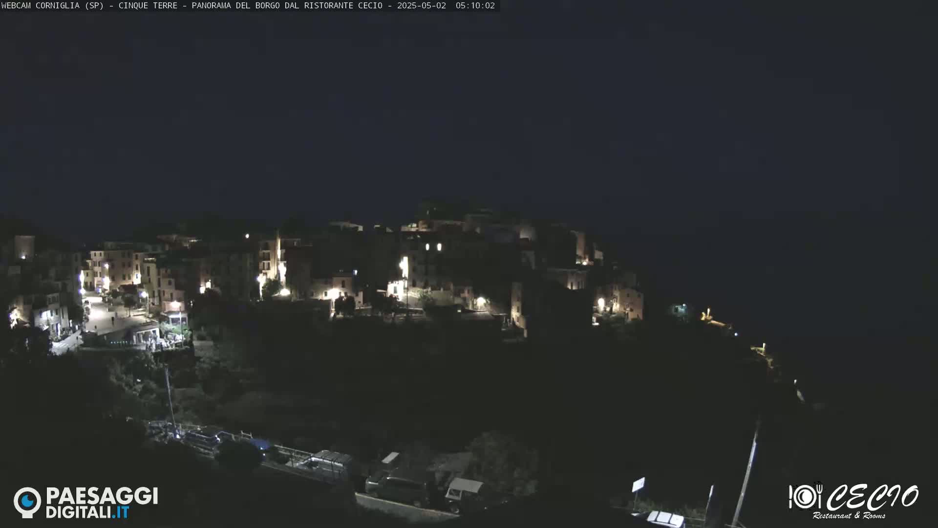 A nighttime view of a small, illuminated town nestled on a dark hillside.