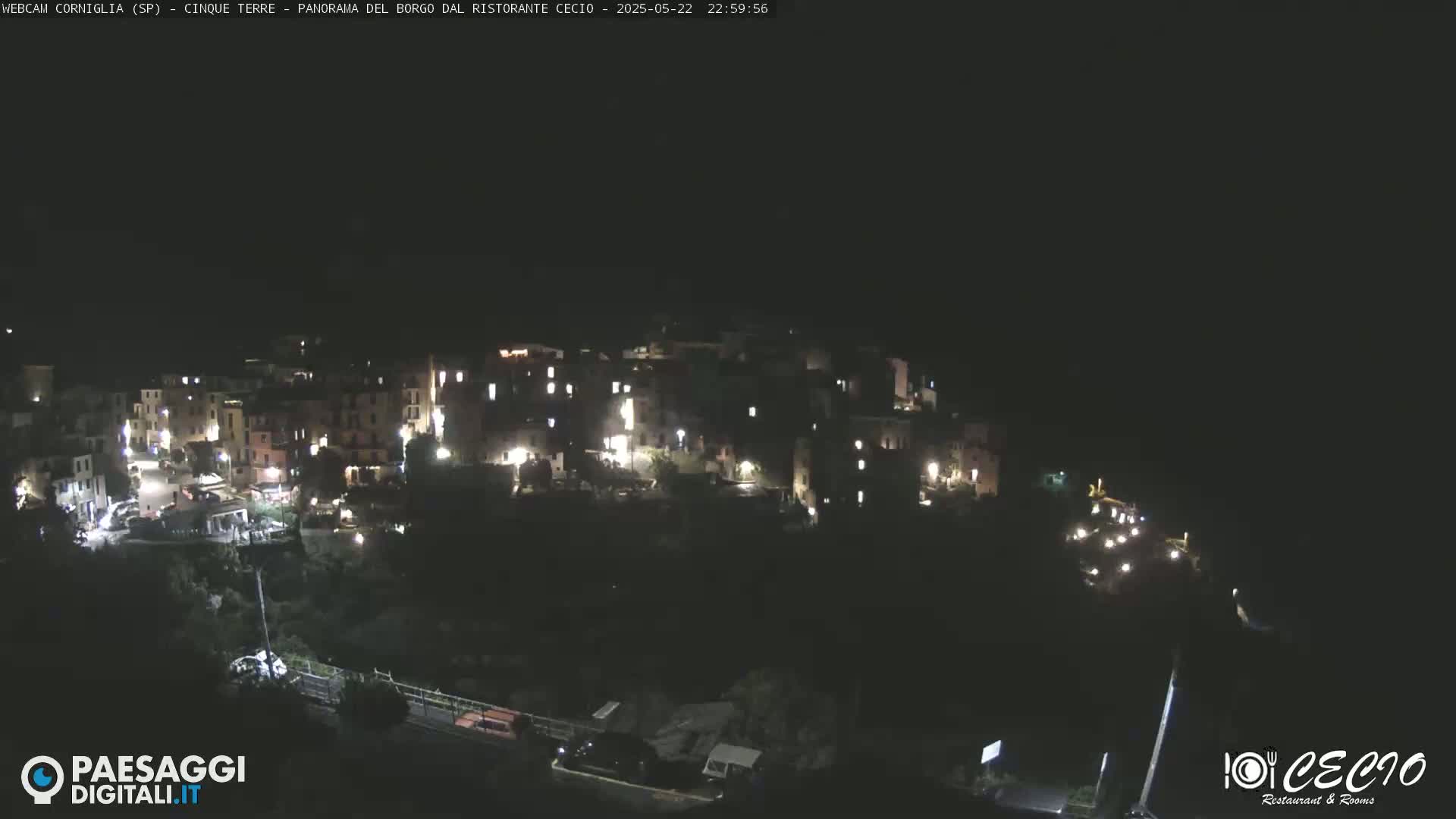 A nighttime, aerial view of a small, illuminated town nestled on a hillside.