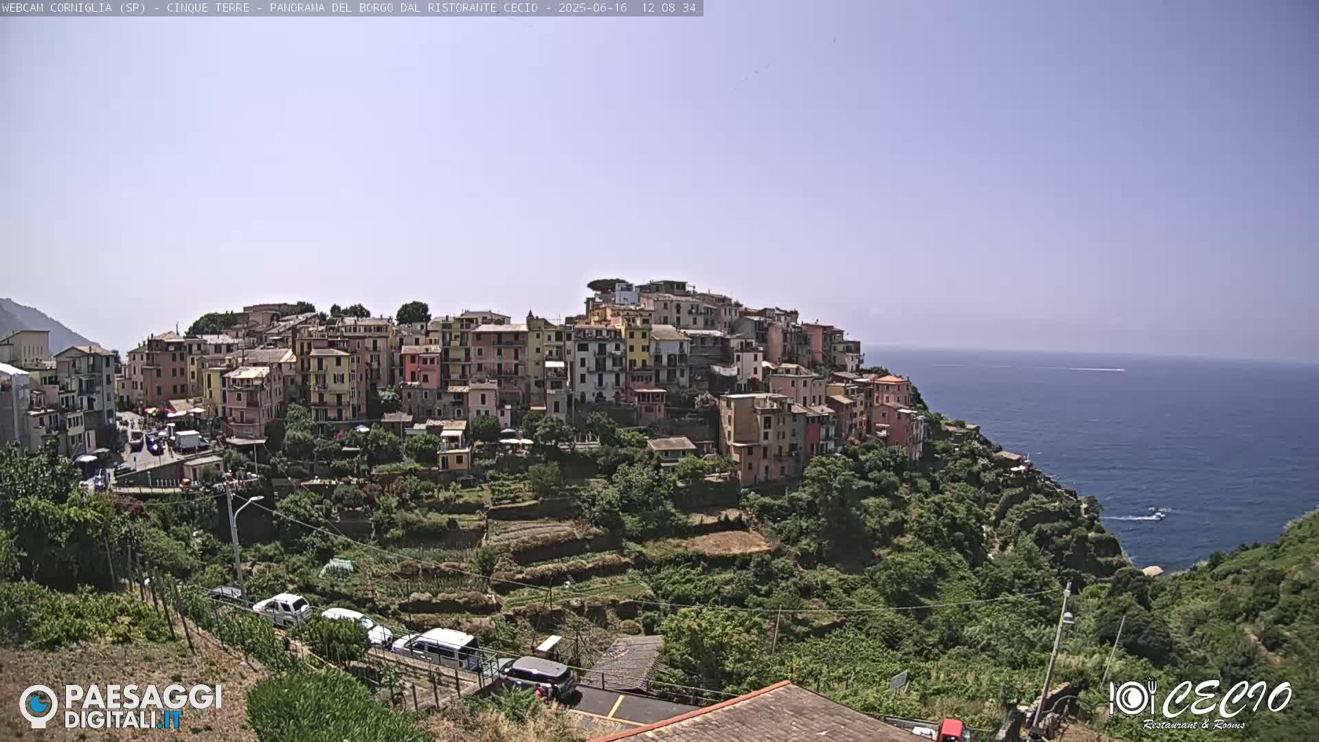 A coastal village of colorful buildings on a hillside overlooking a calm blue sea under a clear sky.