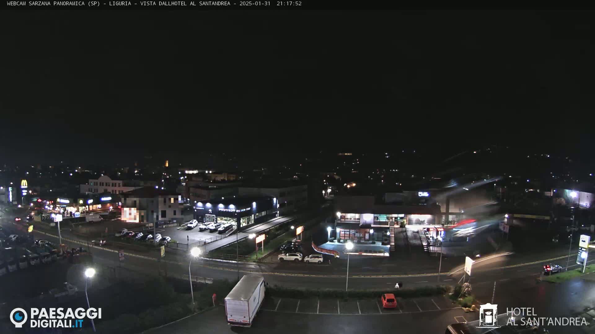 A nighttime aerial view of a town's businesses and roadways under a dark, clear sky.