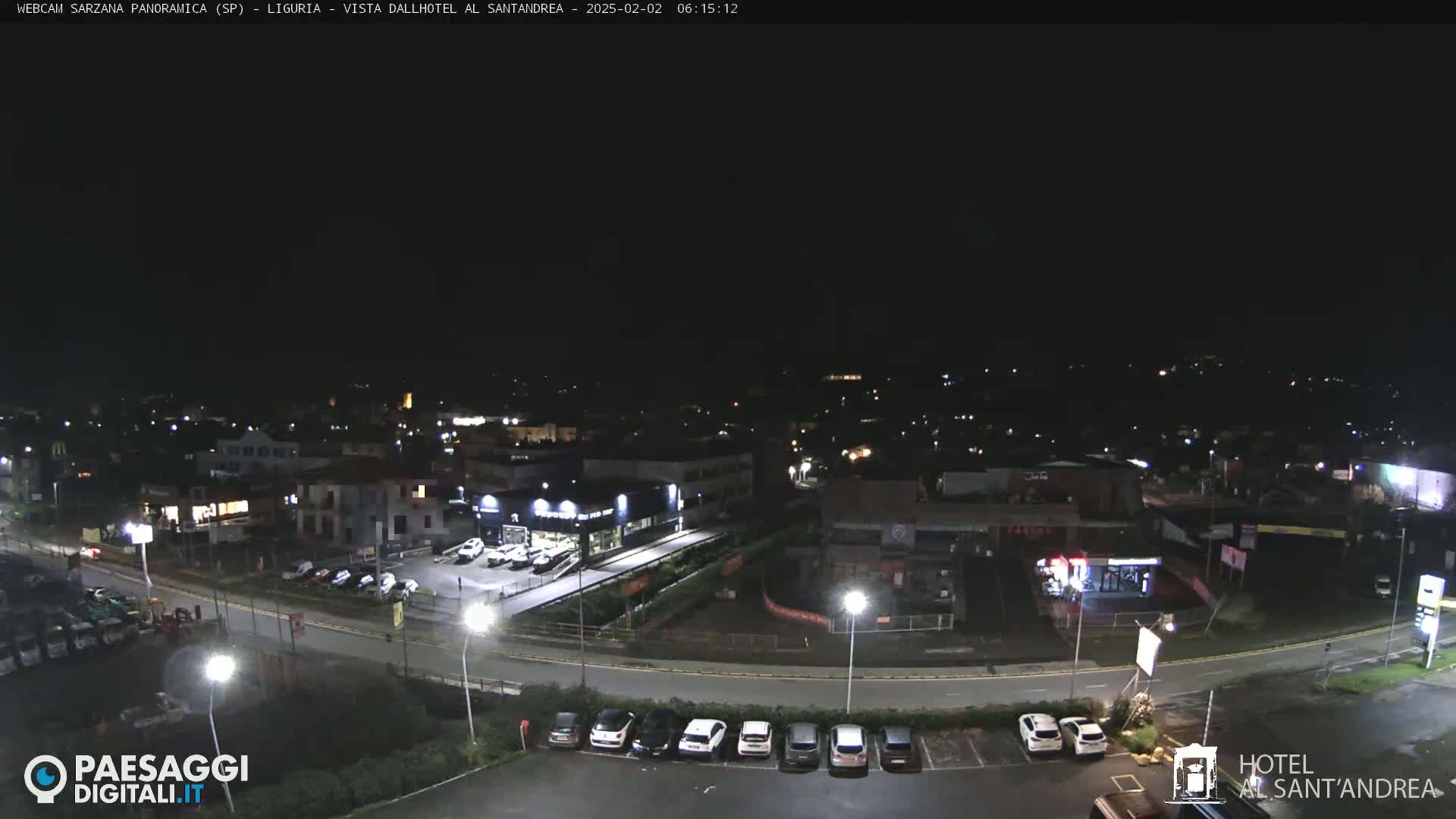 A nighttime, overhead view of a town with streets, cars, and buildings illuminated by artificial lights.