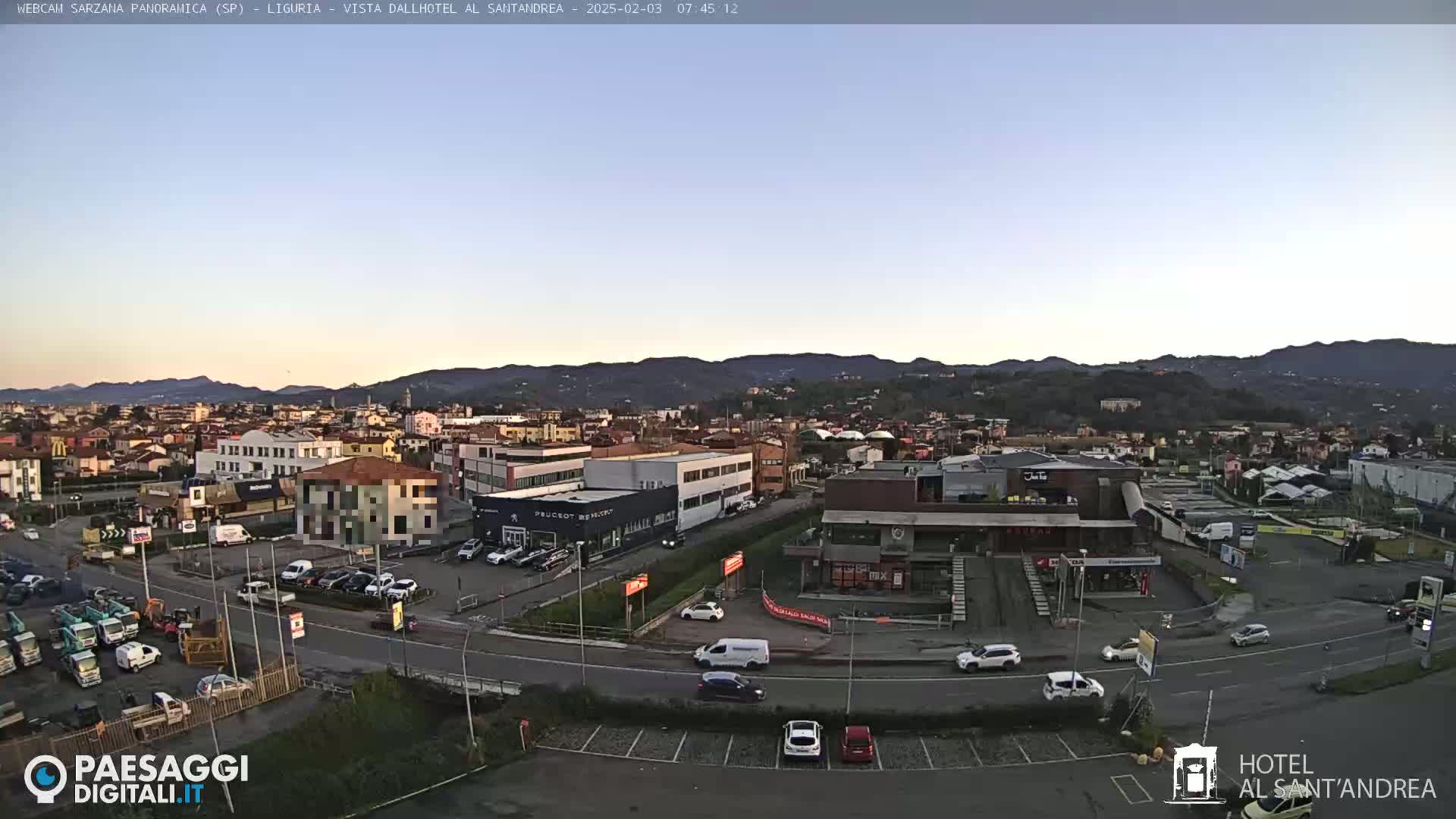 A clear, twilight view of a town situated in a valley, surrounded by mountains.
