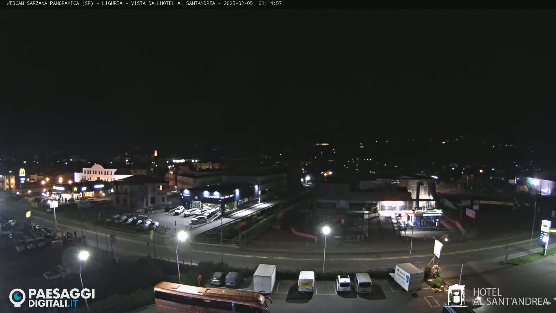 A nighttime aerial view of a town, showing roads, buildings, and parked cars under a clear, dark sky.