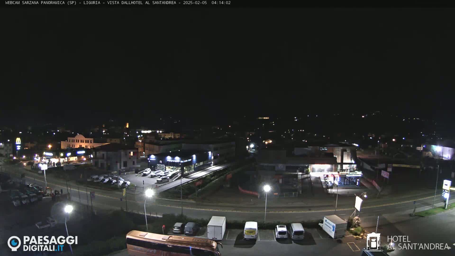 A nighttime, high-angle view of a town's streets and buildings, including parking lots and businesses, under a clear, dark sky.
