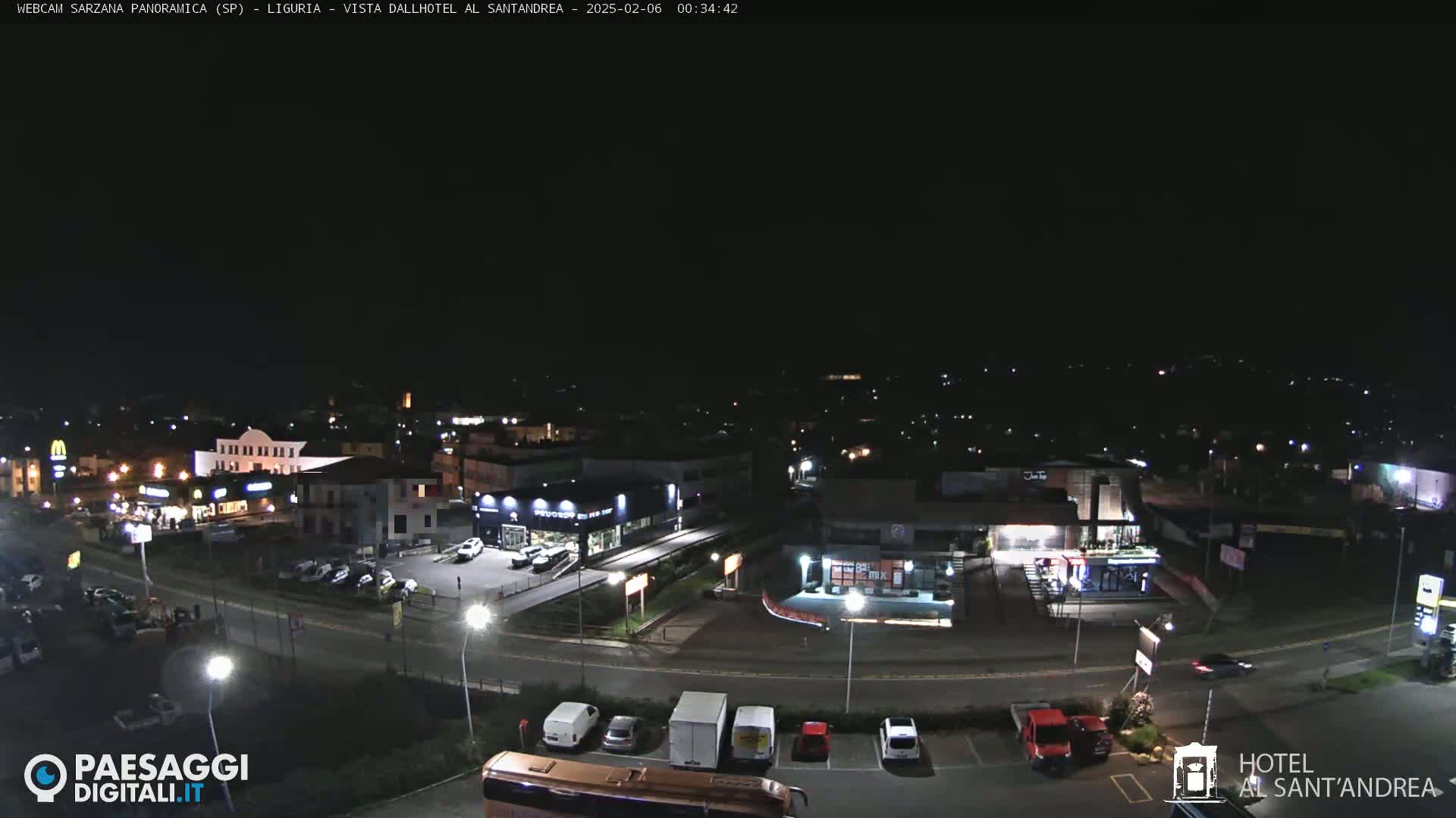 A nighttime, high-angle view of a town with illuminated streets, buildings, and parked cars.