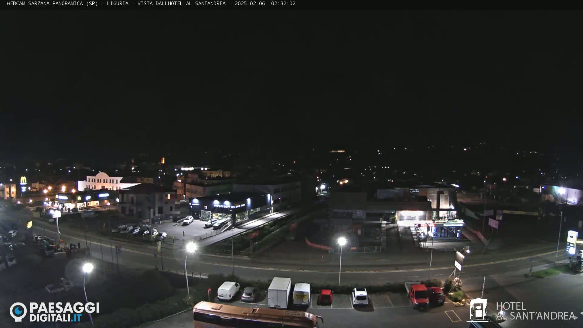 A nighttime, overhead view of a town's streets and parking lots with some businesses illuminated.