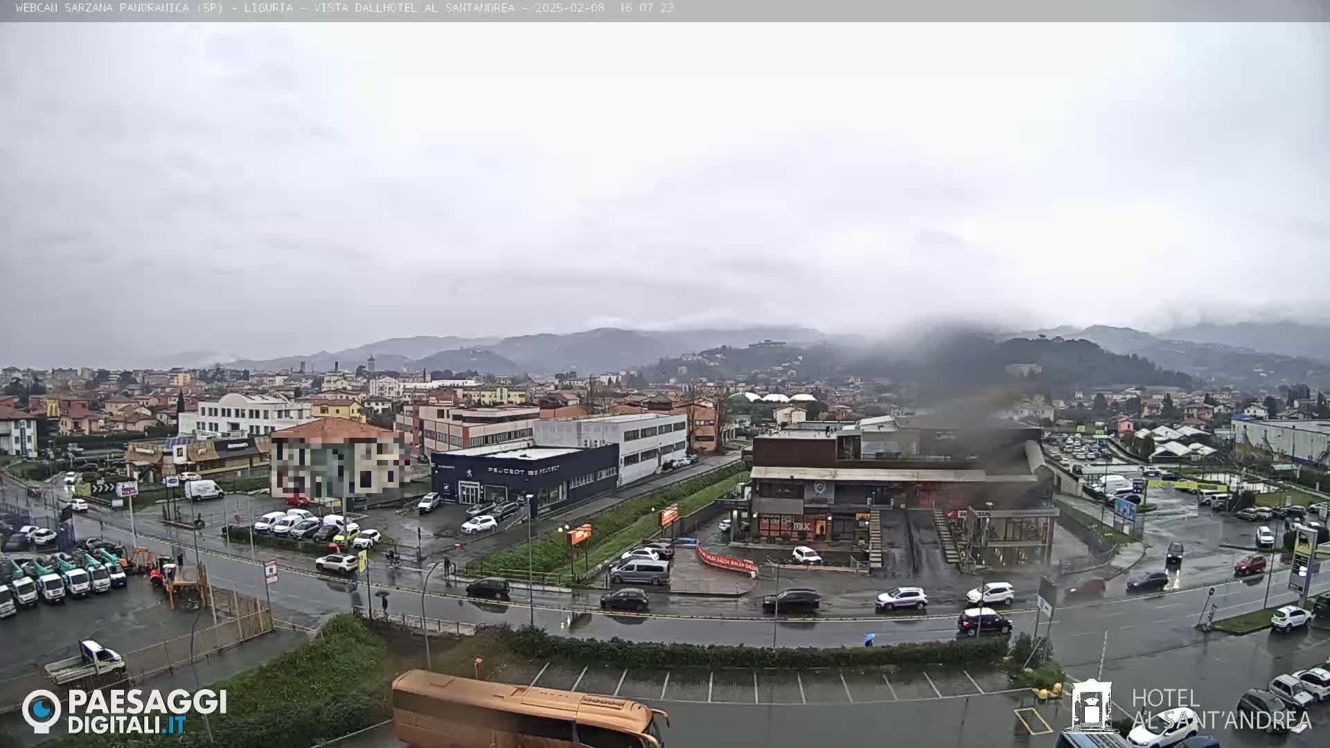 A wide, rain-slicked view of a town and its surrounding hills on an overcast day.