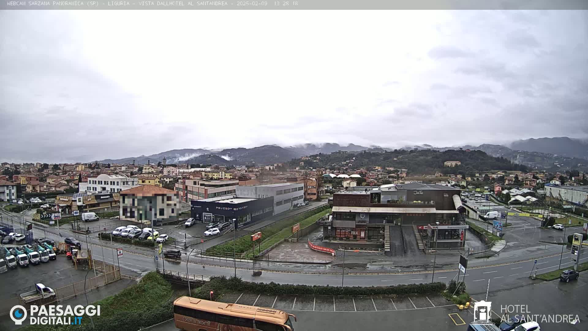 A wet, overcast view of a town nestled in a valley, with mountains shrouded in mist in the background.