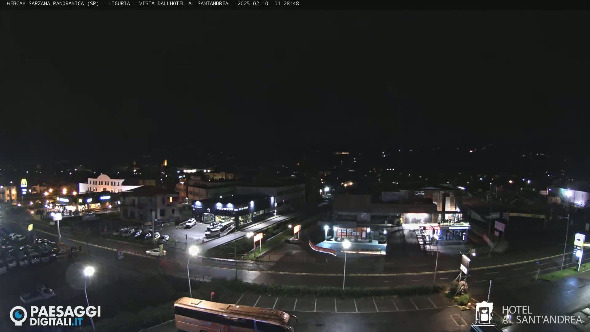 A nighttime, aerial view of a town's streets and buildings, with parking lots and some businesses illuminated.