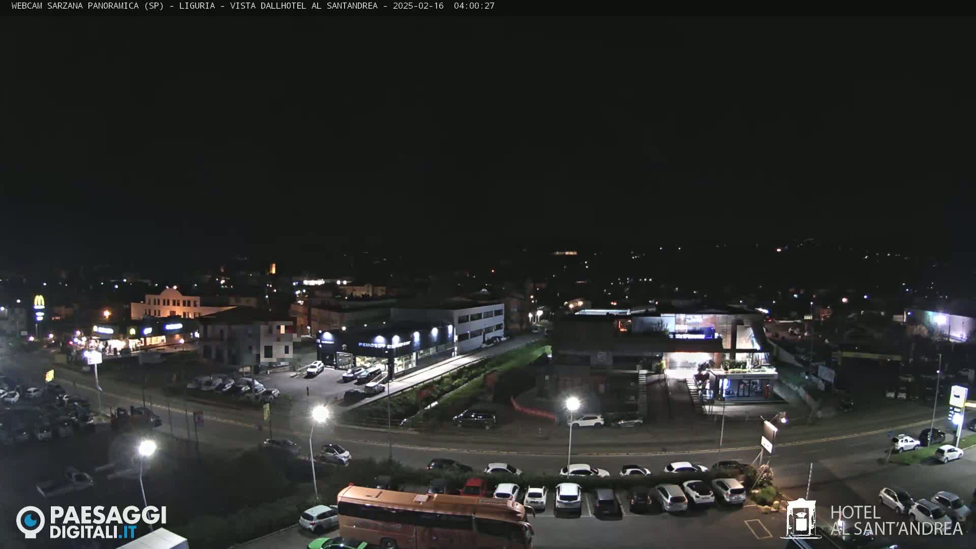 A nighttime, wide shot of a town with parking lots, buildings, and roads illuminated by streetlights.
