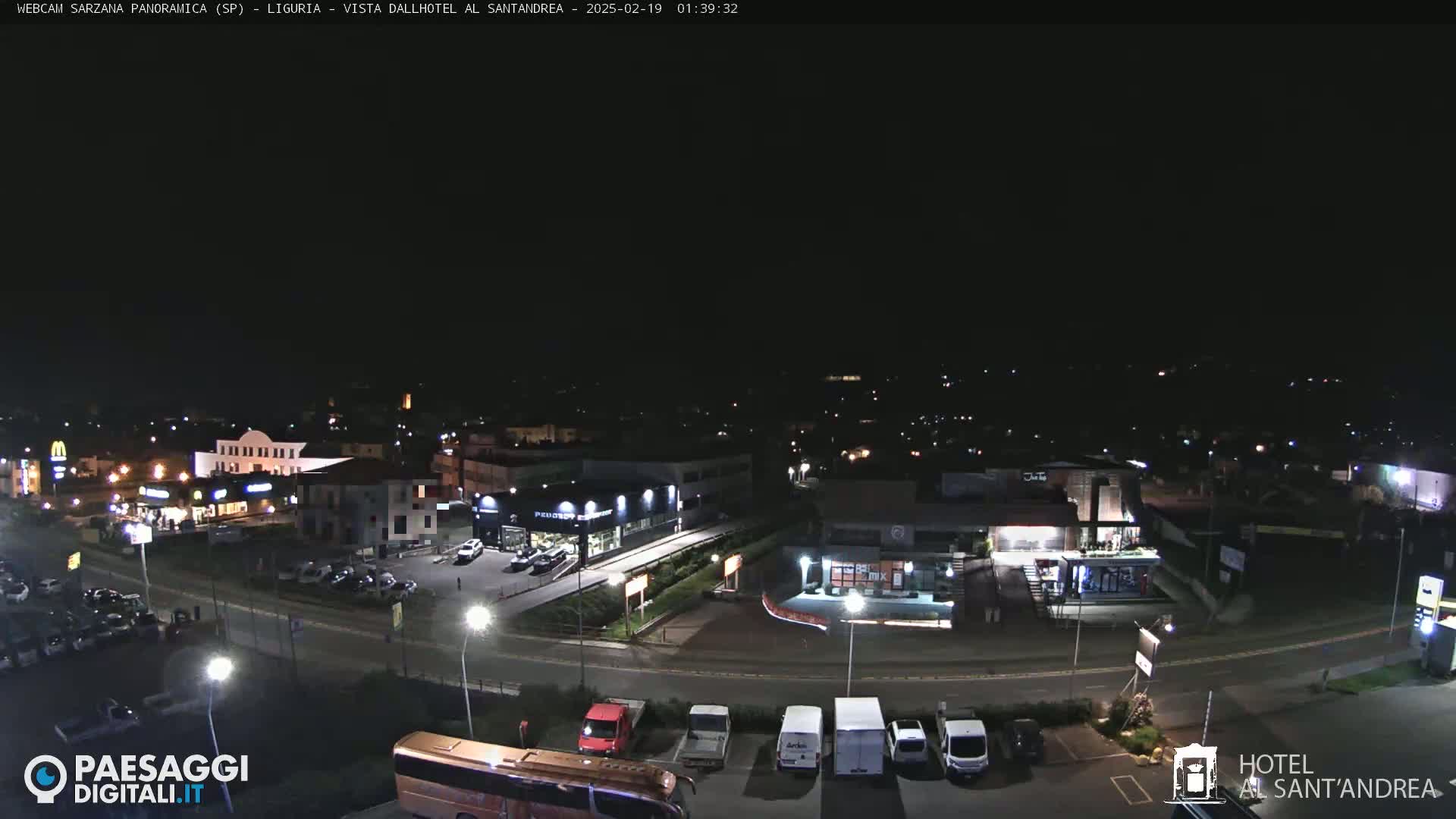 A nighttime, aerial view of a town with roads, buildings, and parking lots illuminated by streetlights.
