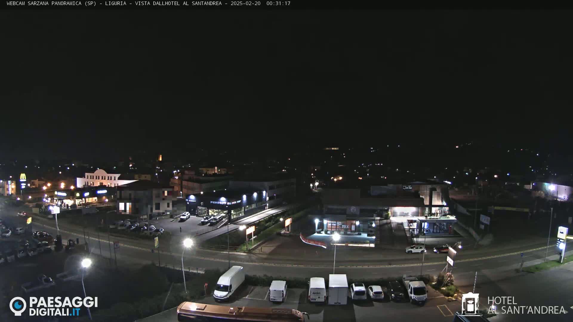 A nighttime aerial view of a town's illuminated streets, parking lots, and buildings.