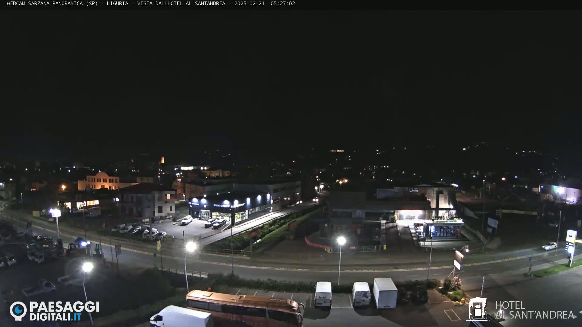 A nighttime, high-angle view of a town with roads, buildings, and parked vehicles.
