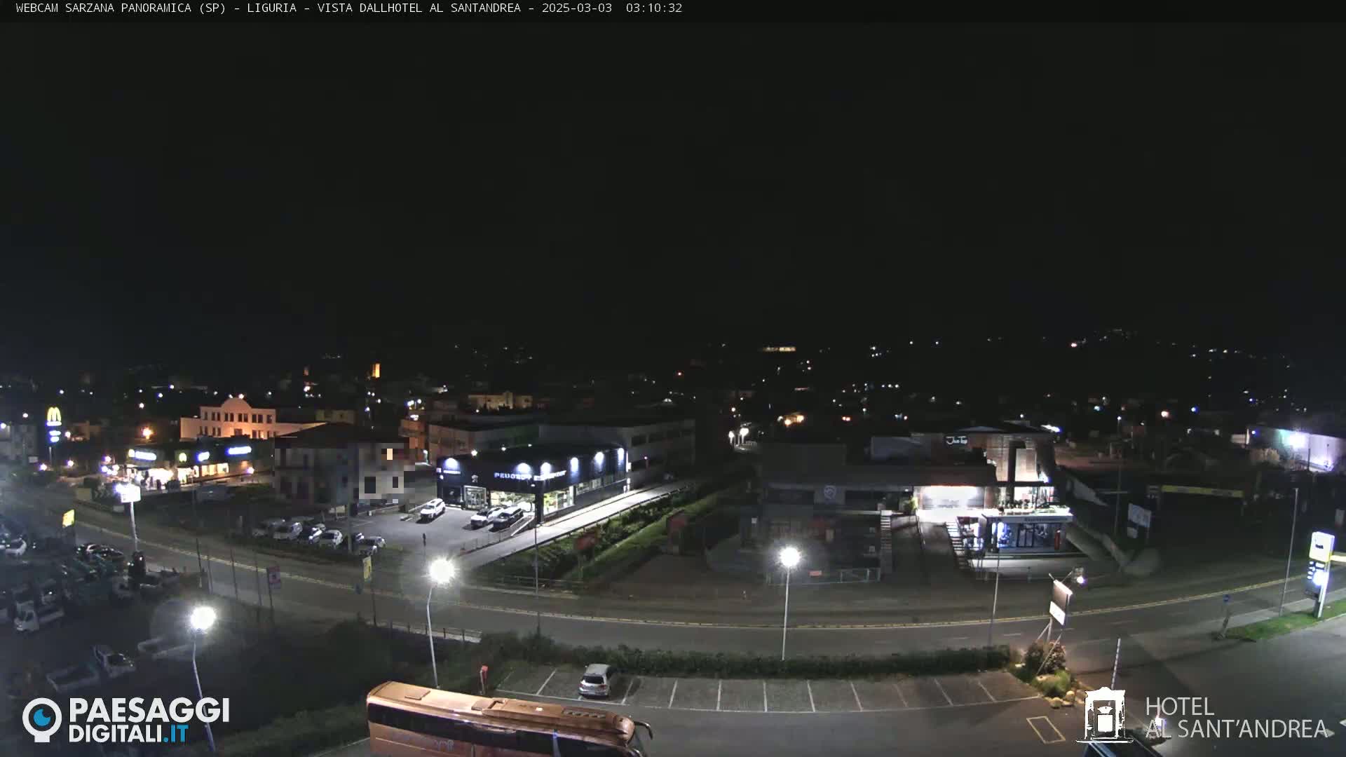 A nighttime, overhead view of a town with roads, buildings, and parking lots, under a clear, dark sky.
