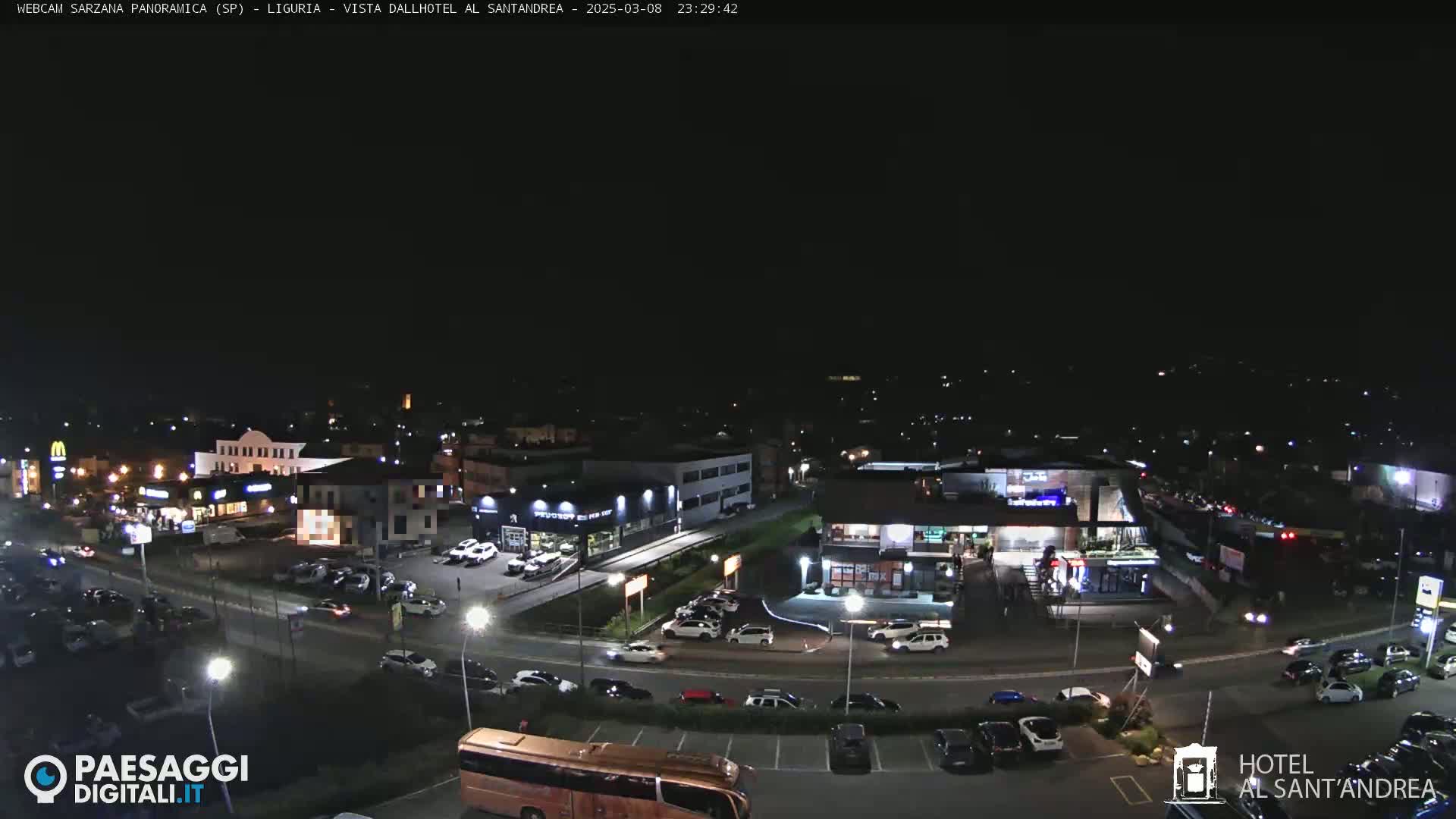 A nighttime aerial view of a parking lot and surrounding businesses, under a clear, dark sky.