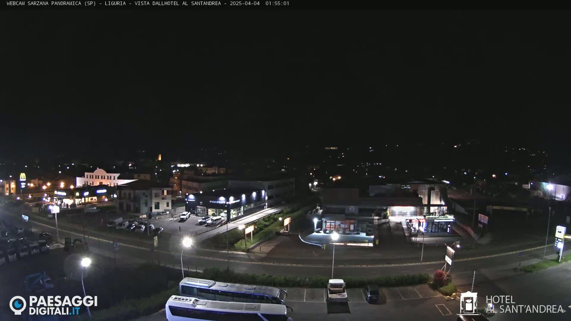 A nighttime, high-angle view of a parking lot and surrounding businesses, illuminated by streetlights.