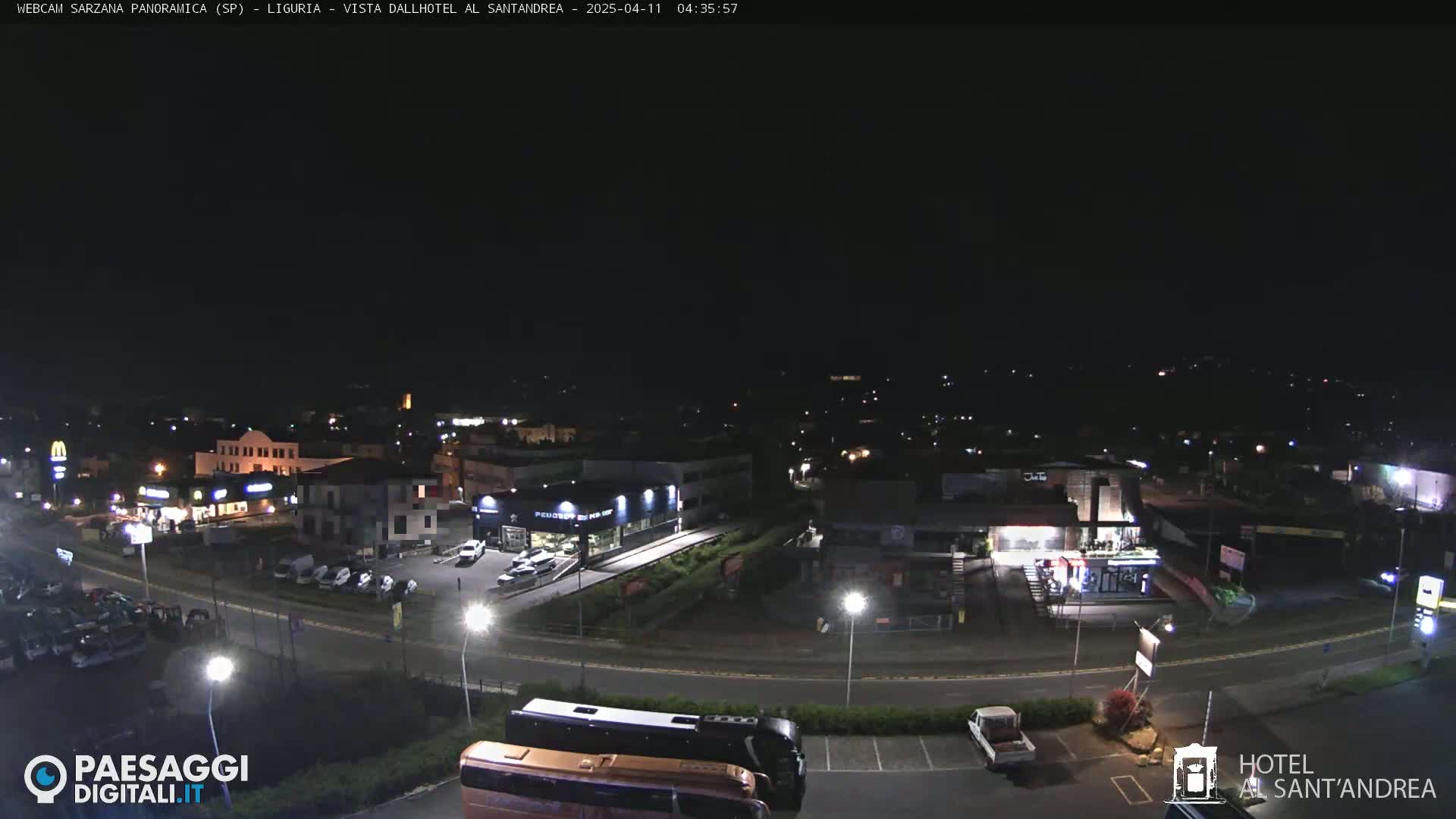 A nighttime aerial view of a town with roads, buildings, and cars, under a clear, dark sky.