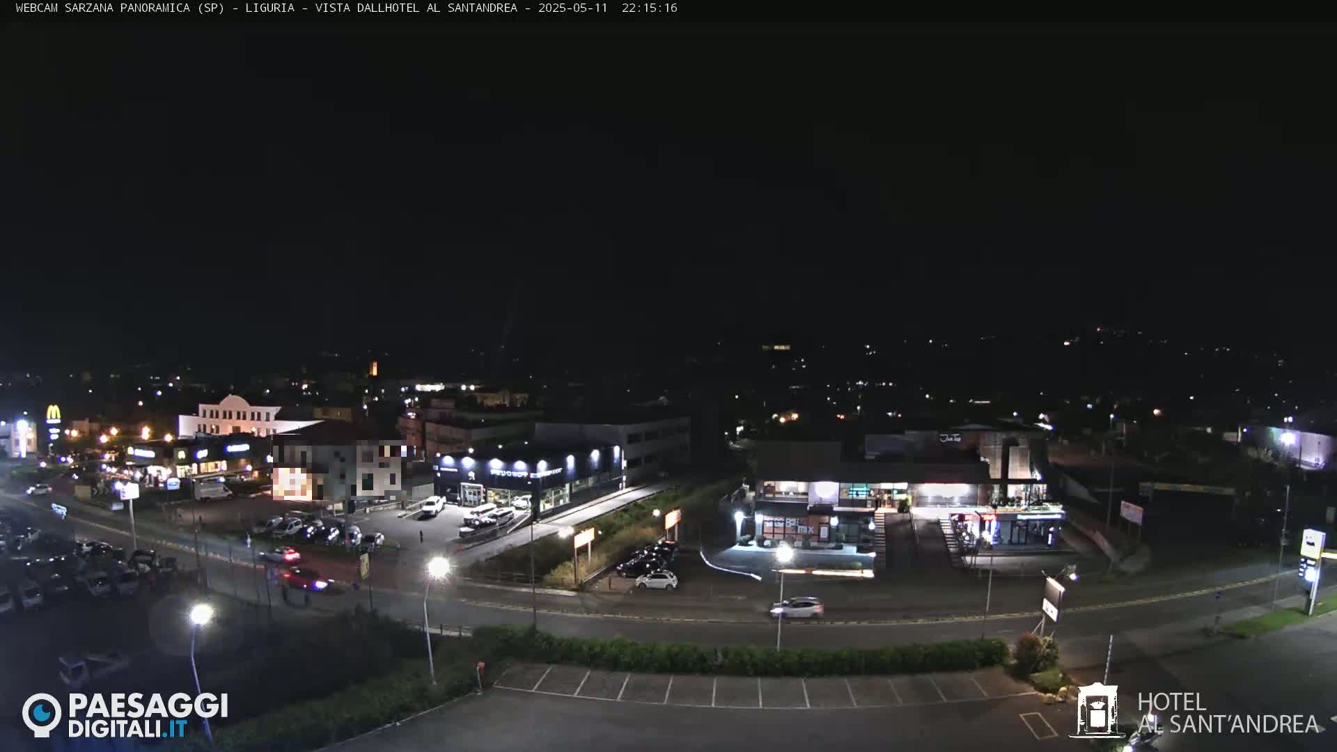 A nighttime aerial view of a parking lot and several illuminated buildings surrounding a roadway.