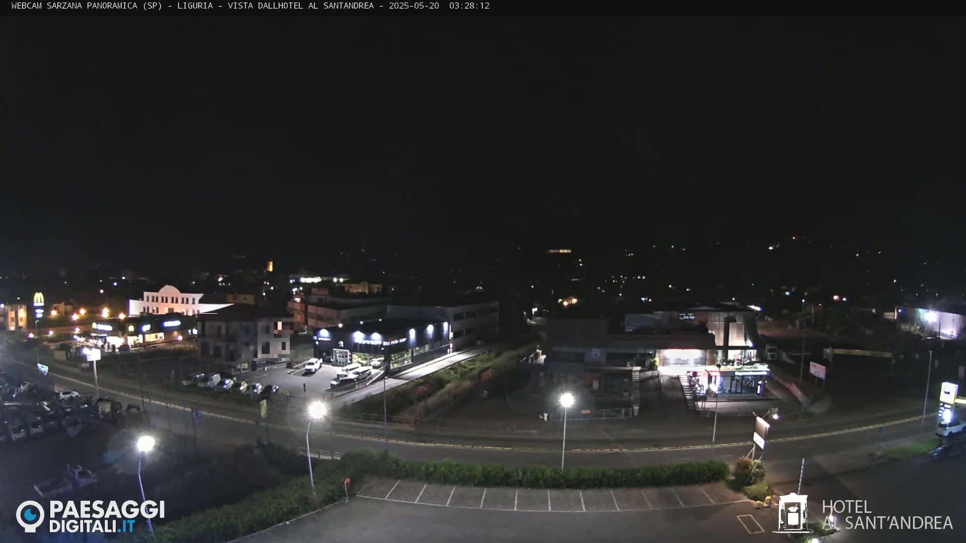 A nighttime aerial view of a town with buildings, roads, and parking lots illuminated by streetlights and building lights.