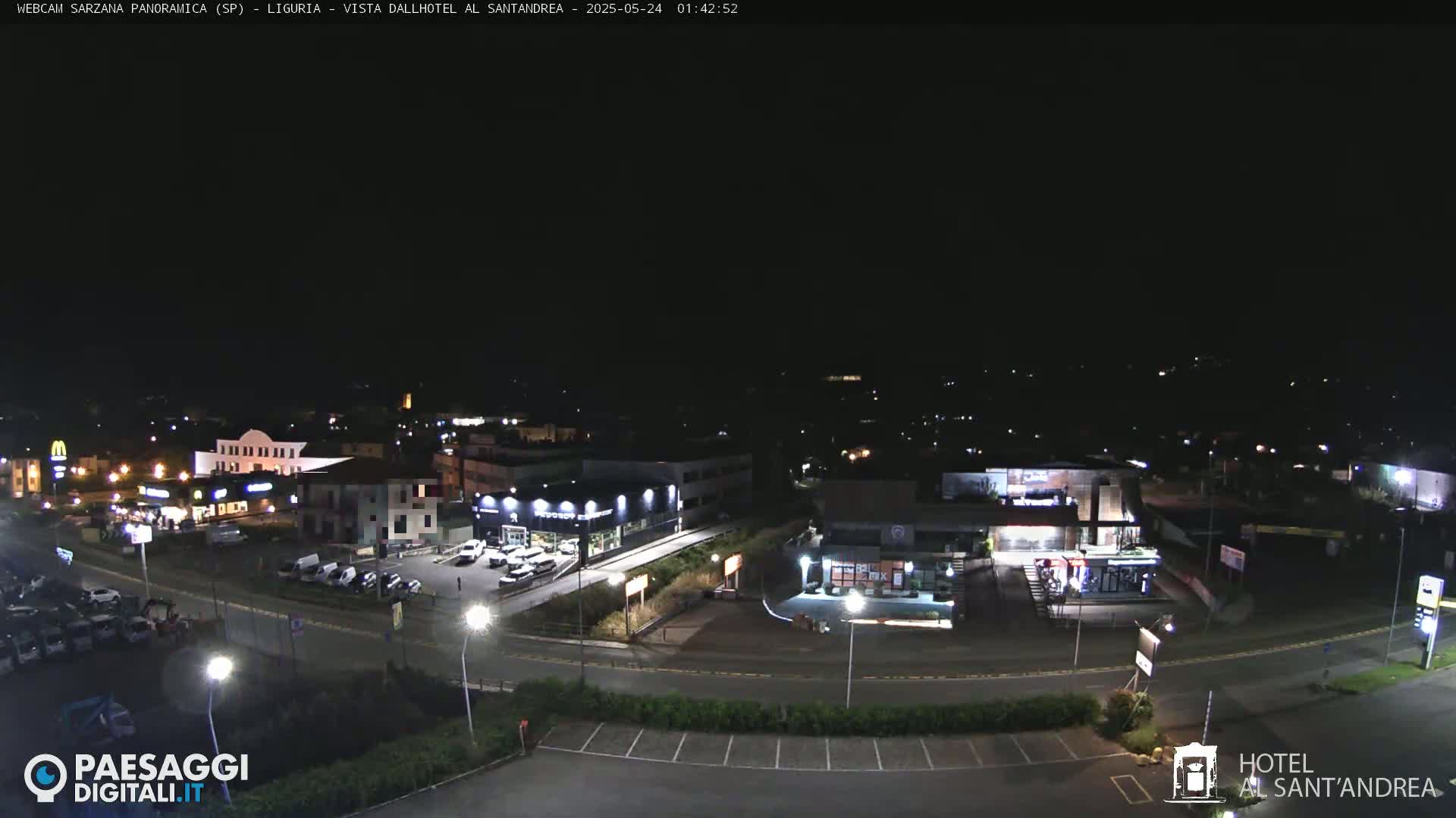 A nighttime, high-angle view of a town's illuminated streets, buildings, and parking lots.