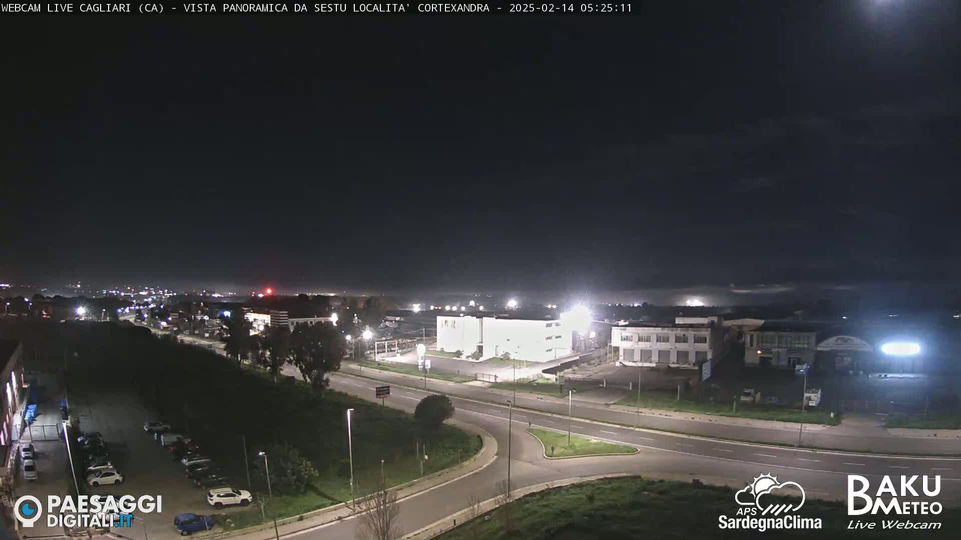 A nighttime, high-angle view of a road intersection and industrial buildings under a dark, clear sky.