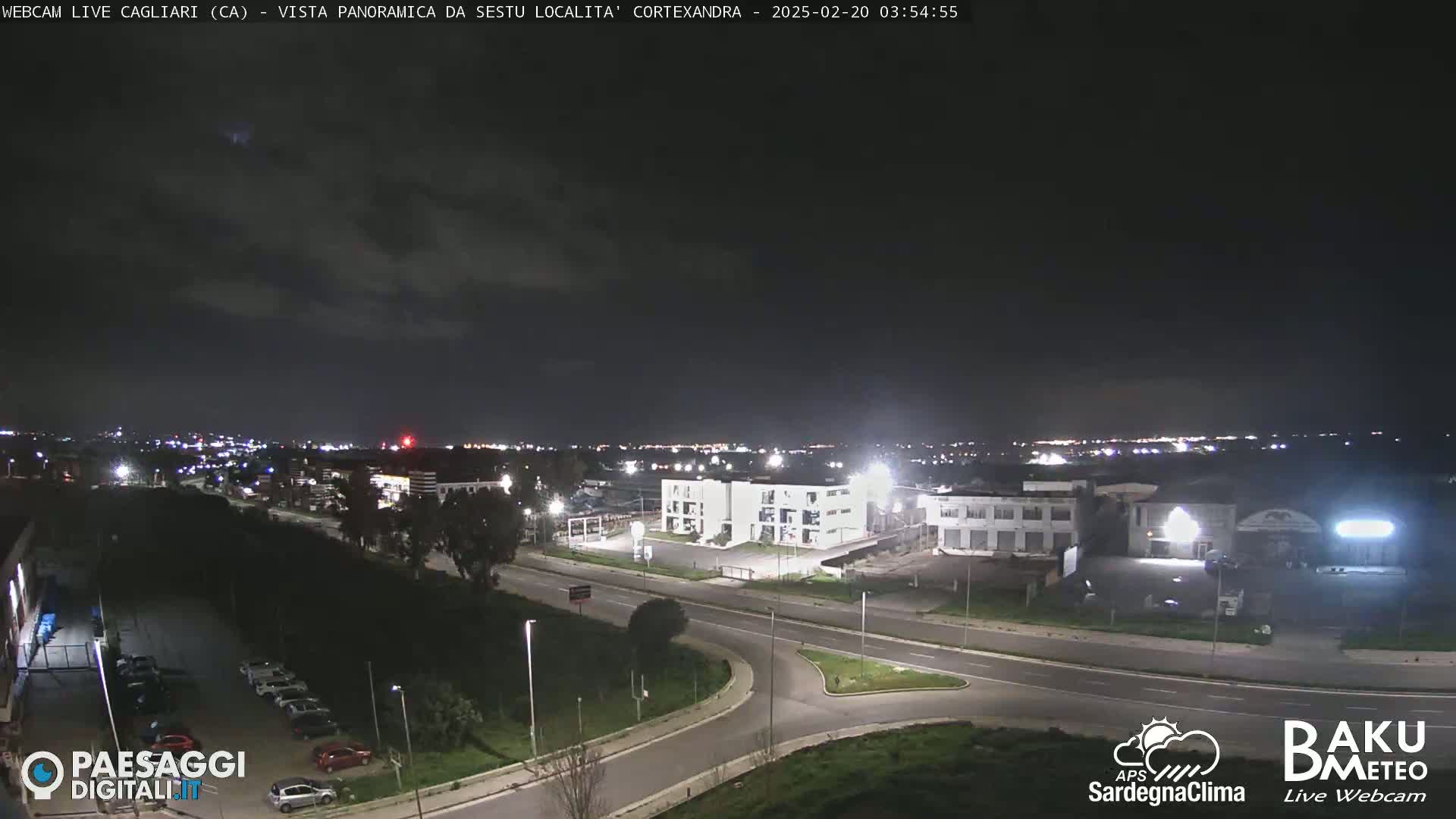 A nighttime, overcast view of a city industrial area with roads and buildings illuminated by artificial lights.