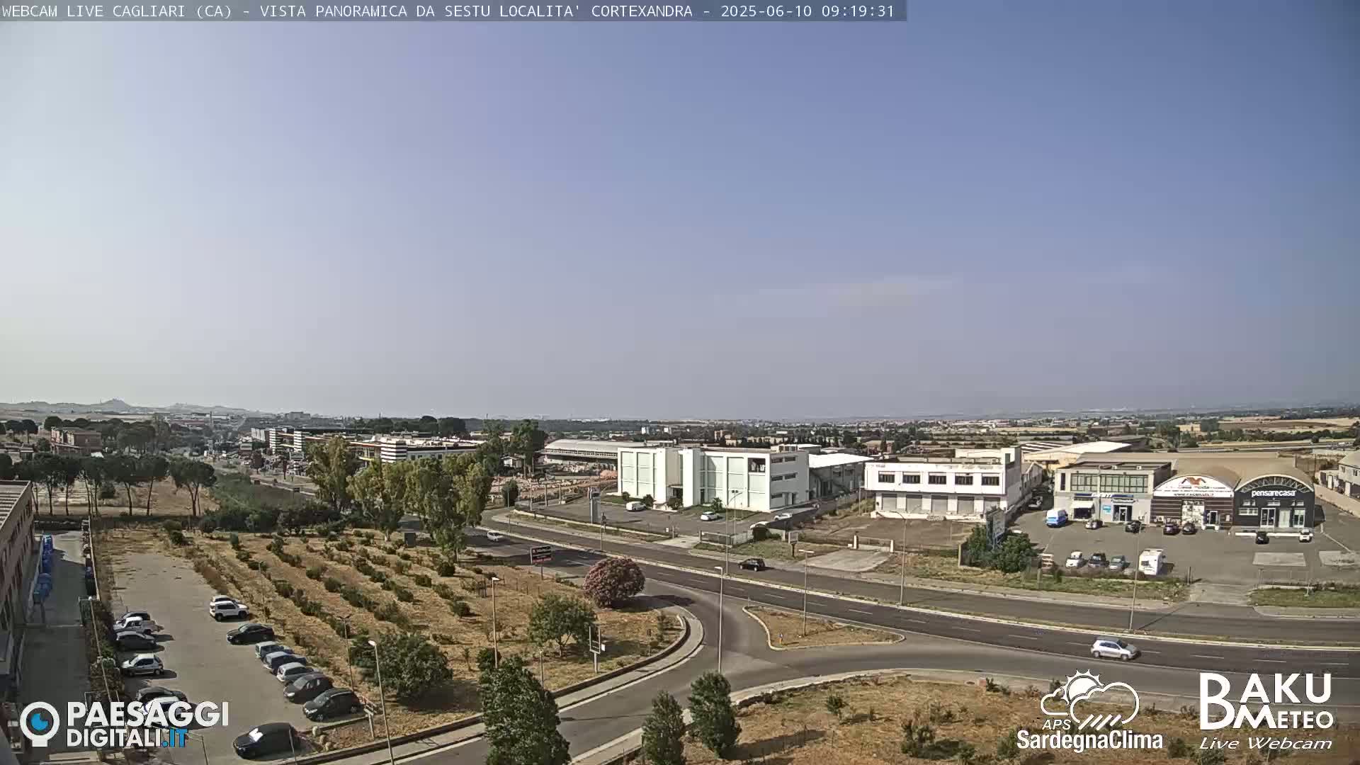 A long shot of an industrial area with light-colored buildings under a clear, bright sky.