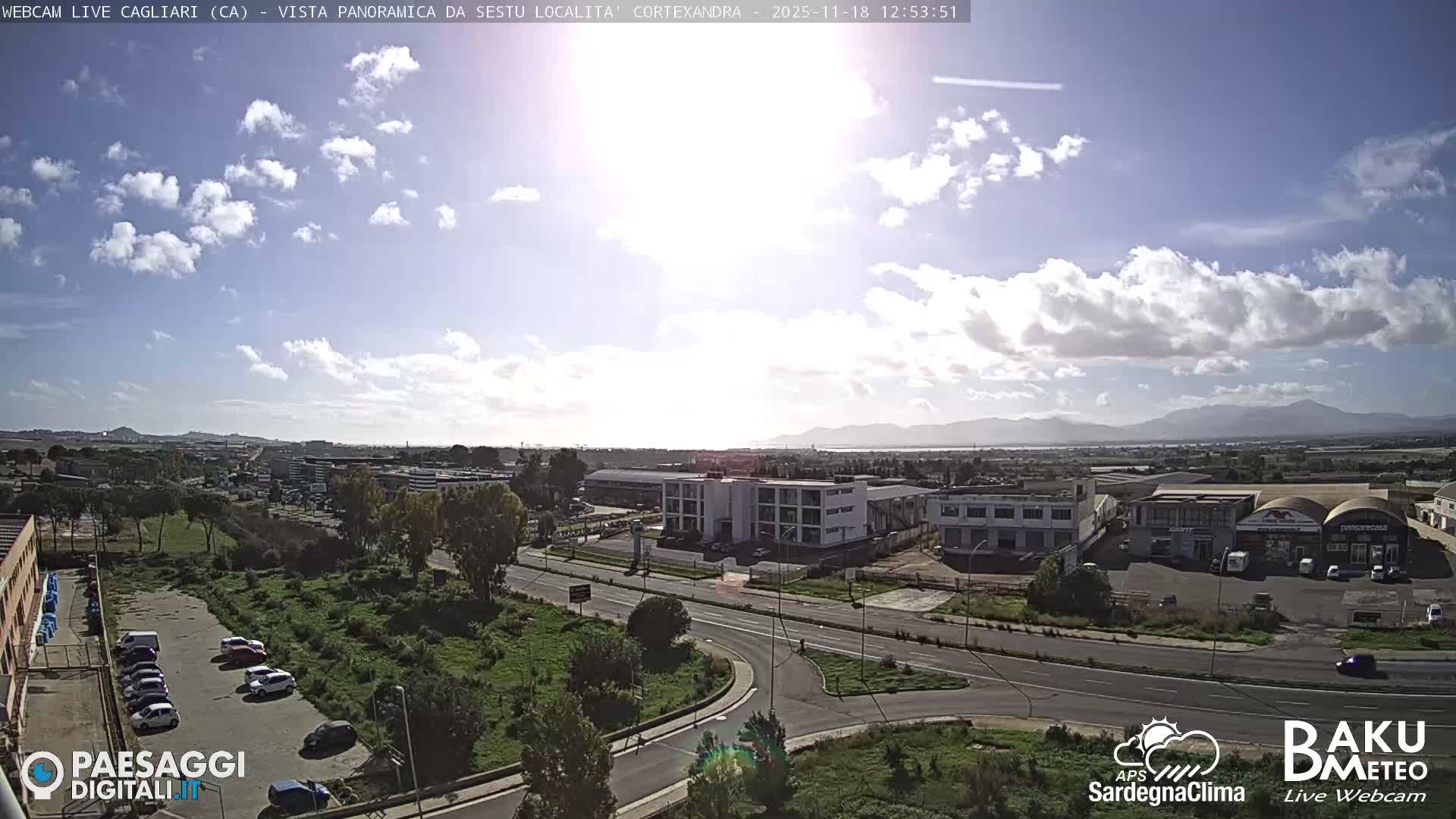 The image displays a nighttime panoramic view of a city with illuminated roads, several buildings, a parking lot with cars, and distant urban lights under a dark, clear sky.