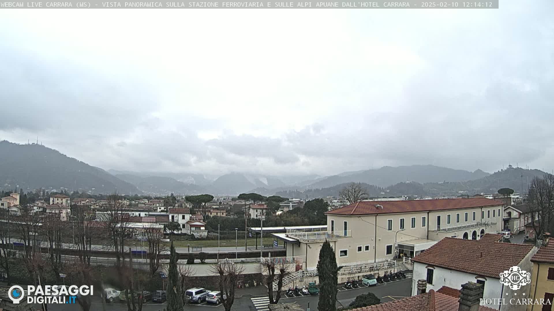 A panoramic view of a town nestled in a valley between mountains on an overcast day.
