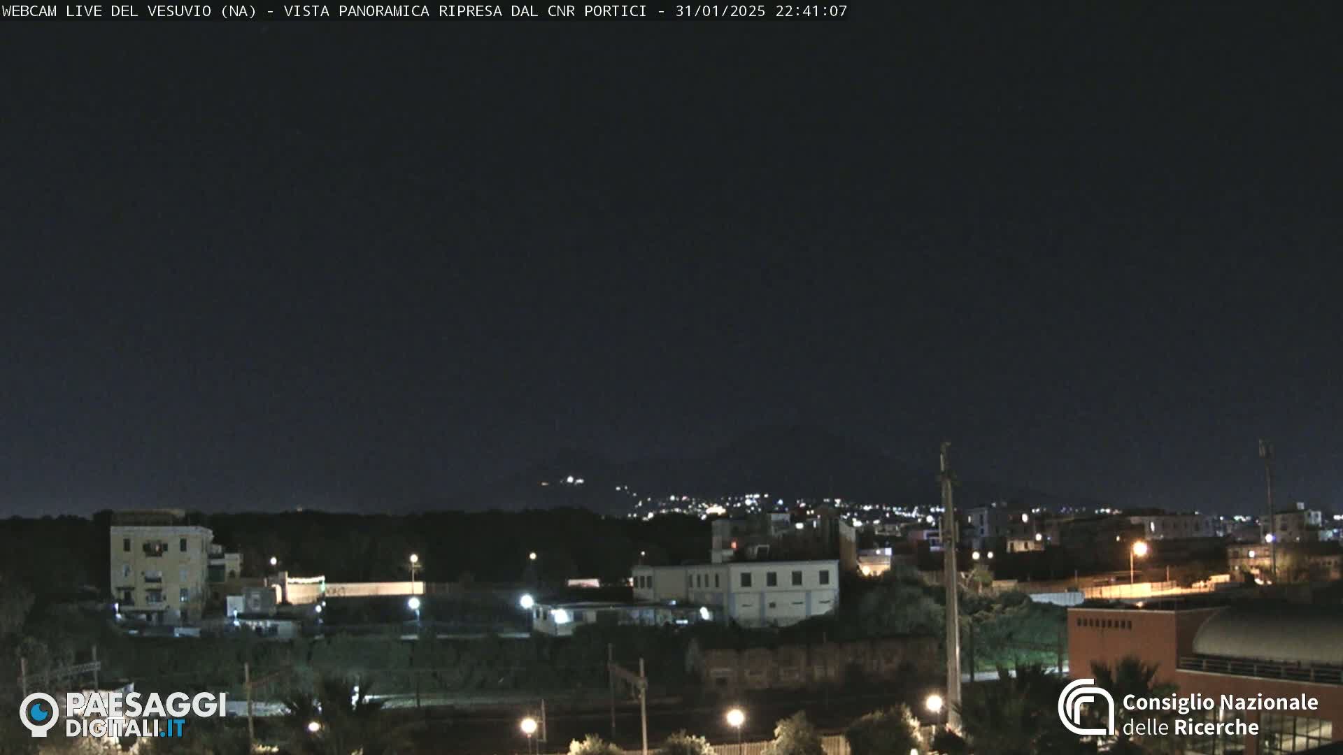 A nighttime long shot of a town with low-level lighting under a clear, dark sky.