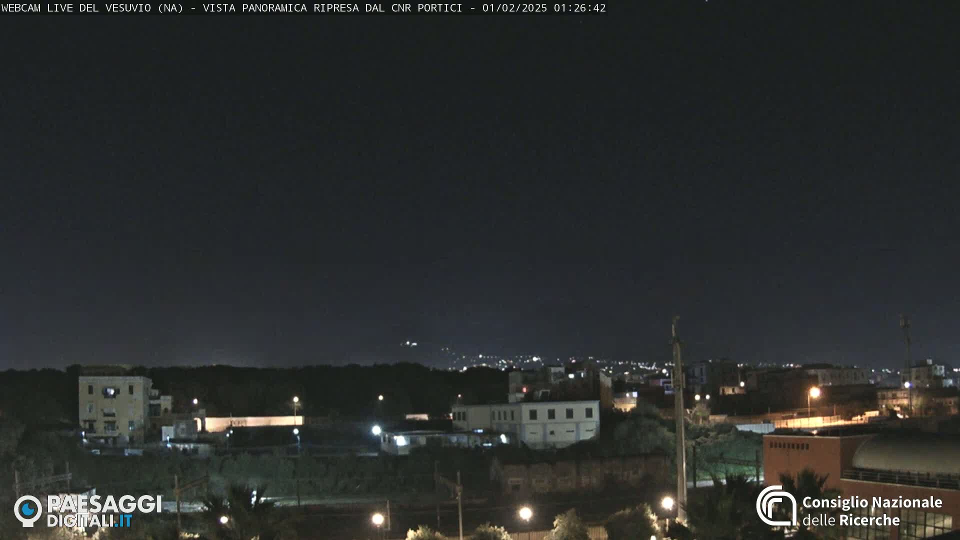 A nighttime long shot of a city skyline under a clear, dark sky.
