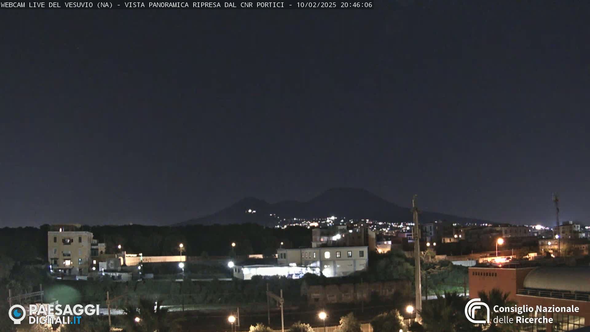 A nighttime view of a city with mountains in the distance under a clear, dark sky.