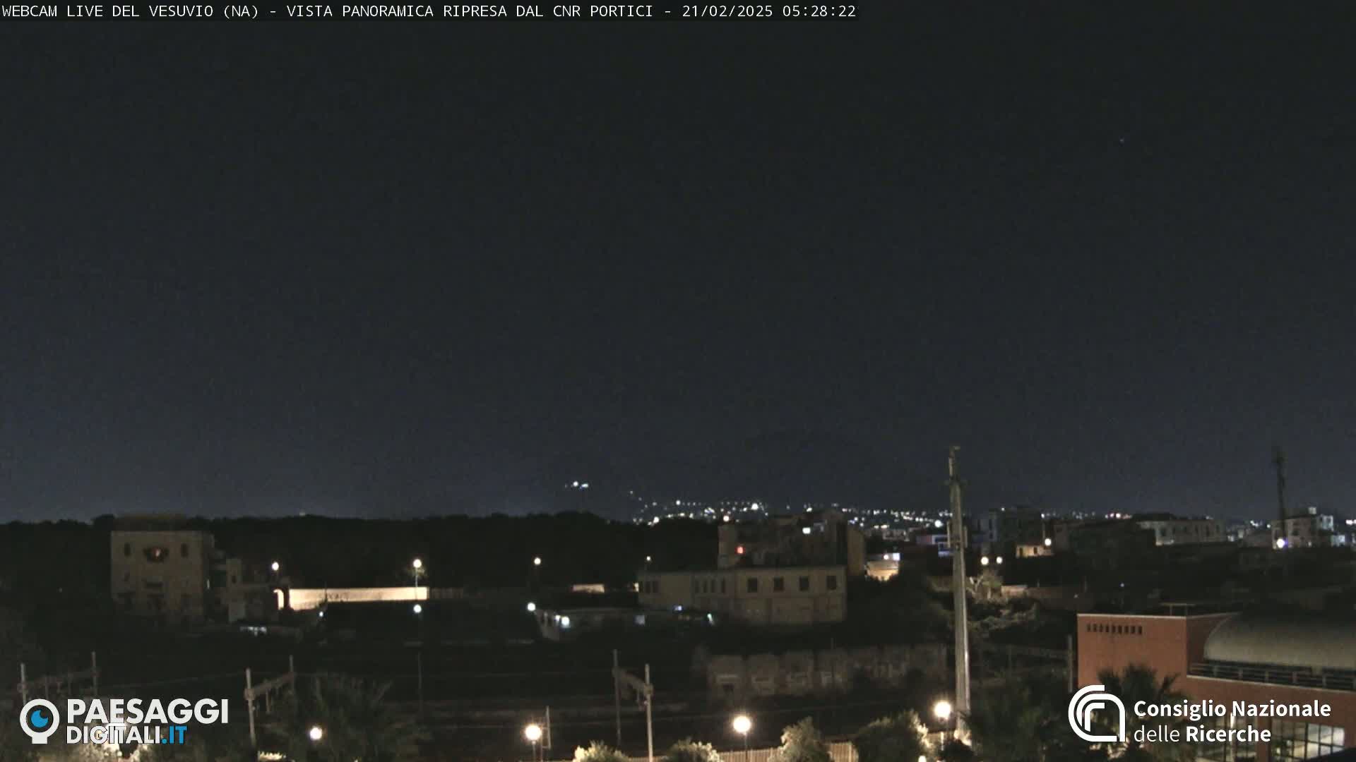 A nighttime view of a city skyline under a dark, clear sky.
