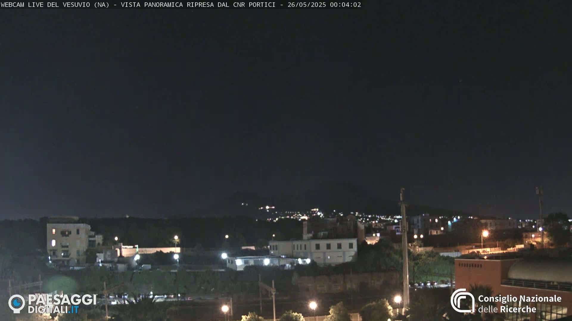 A nighttime, long shot of a city illuminated by artificial lights under a dark, clear sky.