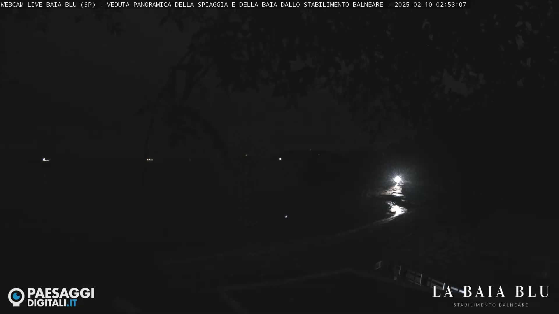 A nighttime, low-light view of a dark, mostly obscured landscape with a bright light source visible in the lower right corner.
