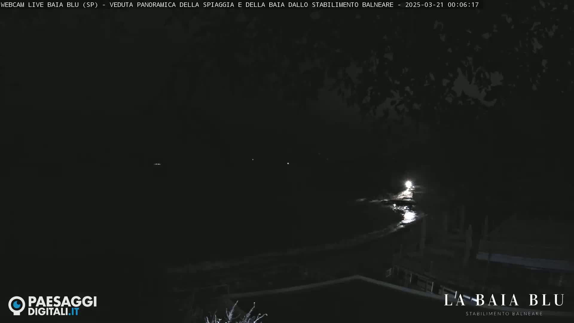 A nighttime, low-light view of a dark body of water, possibly a bay, with faint lights visible in the distance.