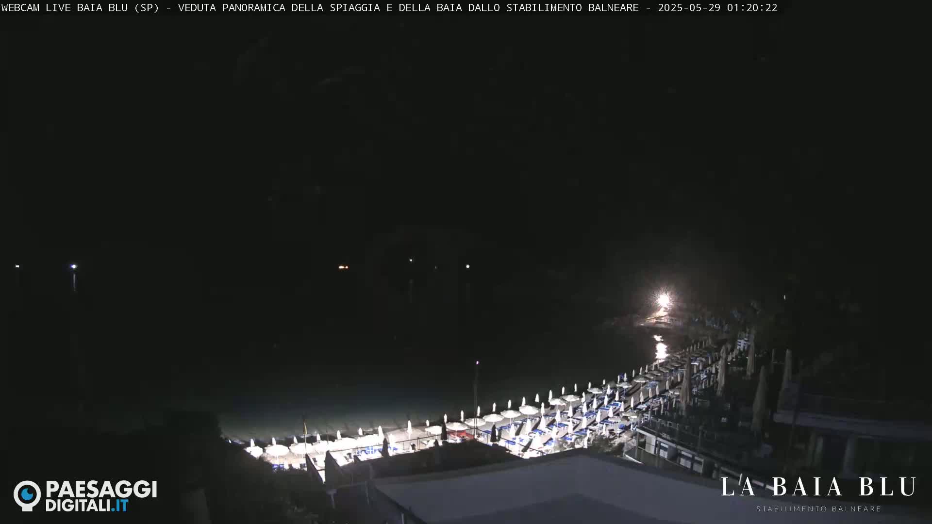 A nighttime, panoramic view of a beach with rows of closed umbrellas and chairs.