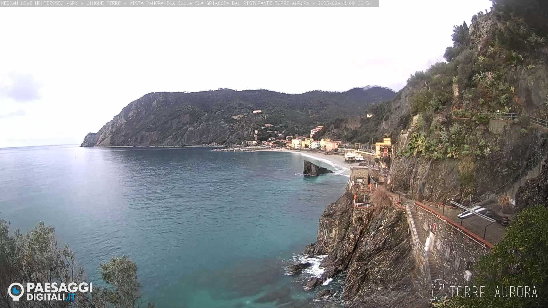 A coastal town nestled between steep cliffs and the sea on an overcast day.