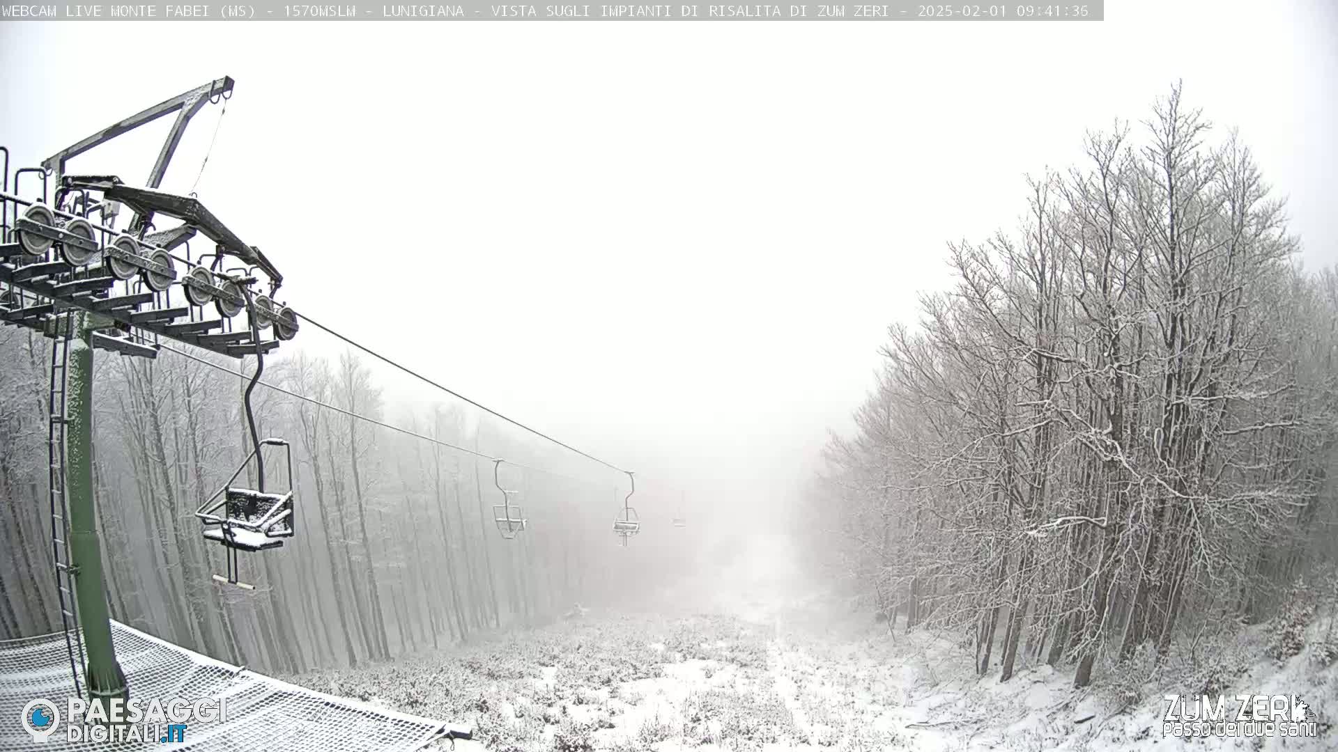 A snow-covered ski lift ascends through a foggy, snow-laden forest.