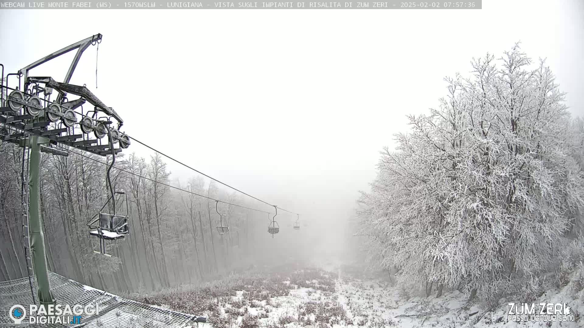 A chairlift ascends a snowy, foggy mountainside through a forest of snow-covered trees.