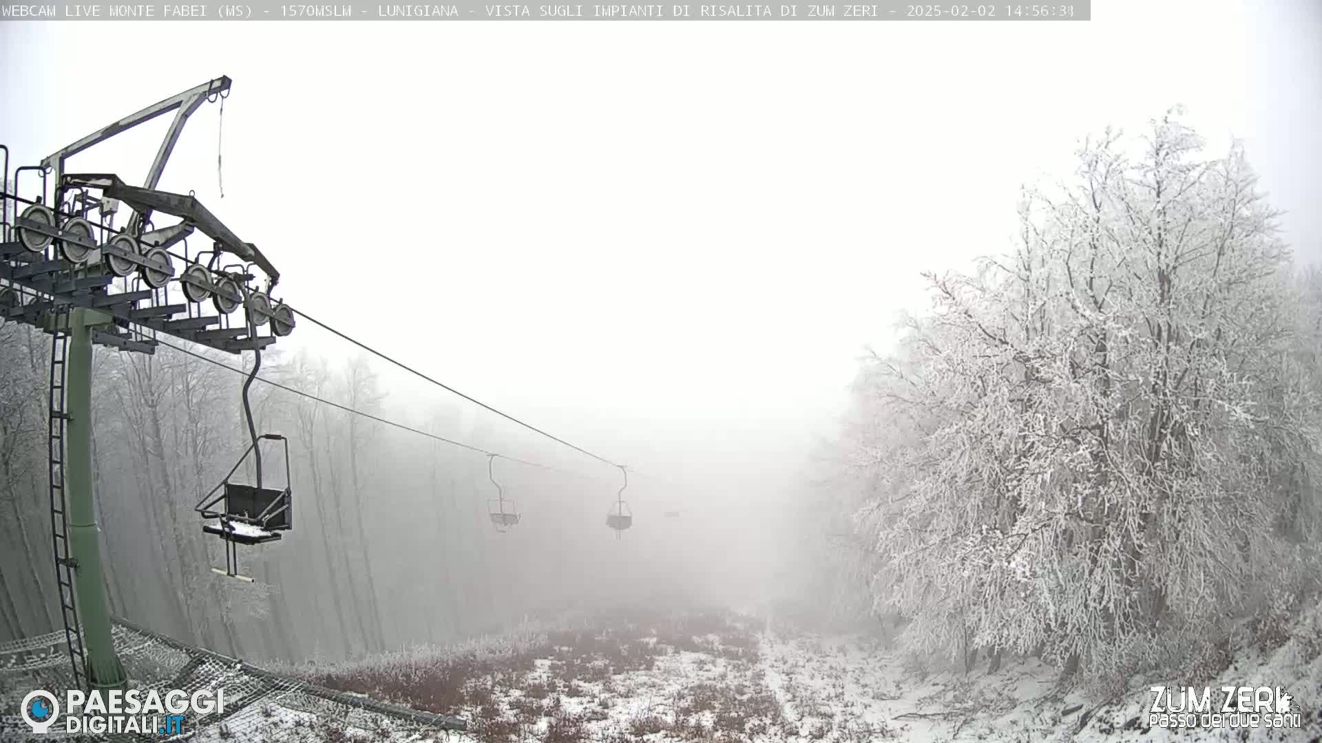 A chairlift ascends through a foggy, snow-covered landscape.