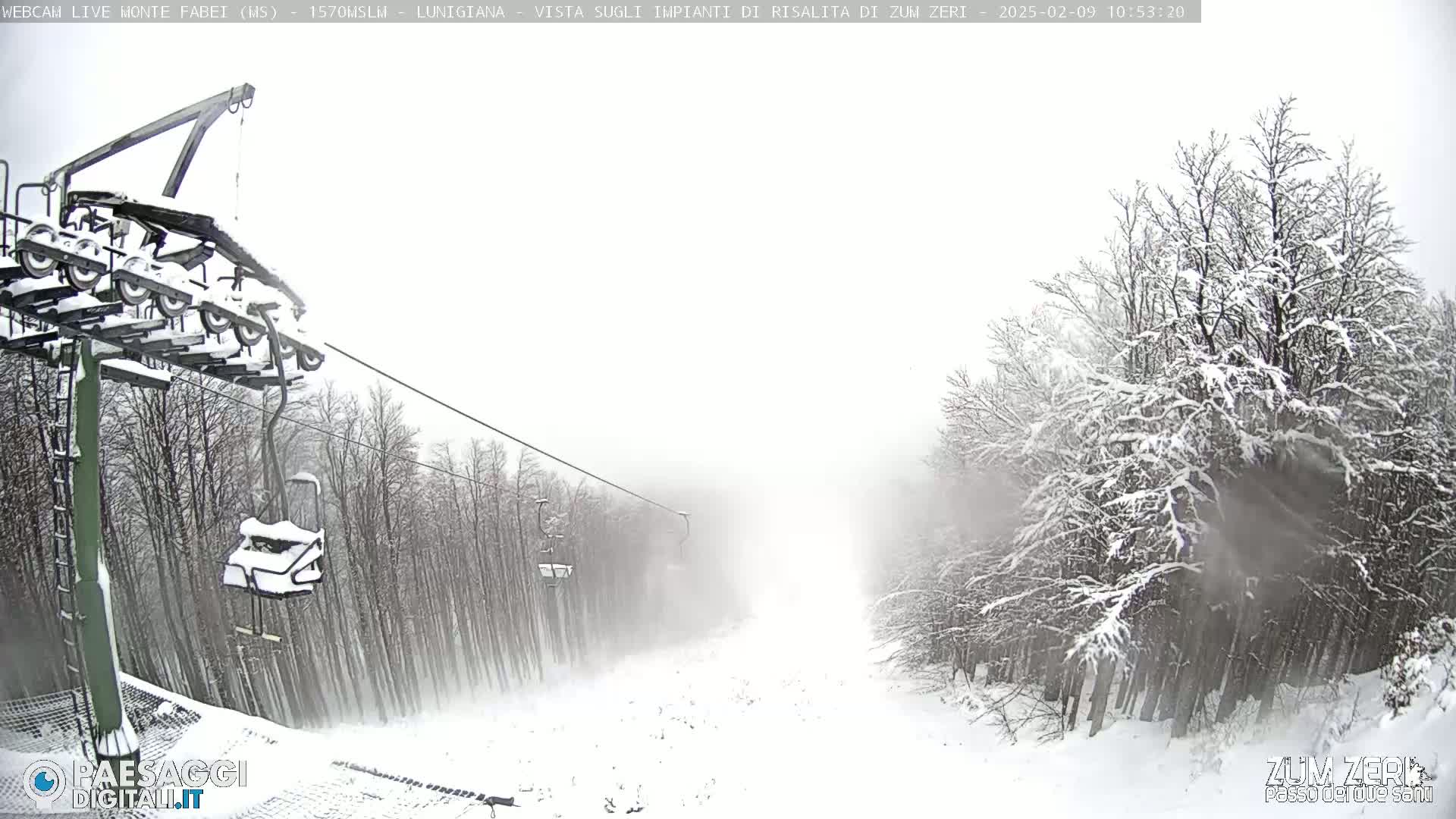 A snow-covered ski lift and snowy trees are visible in heavy snowfall.