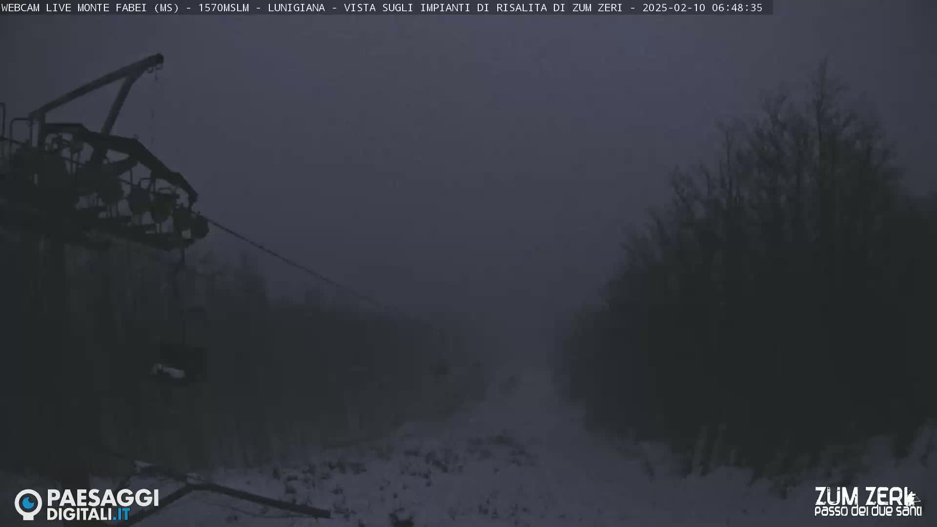A chairlift hangs over a snow-covered landscape shrouded in thick fog.