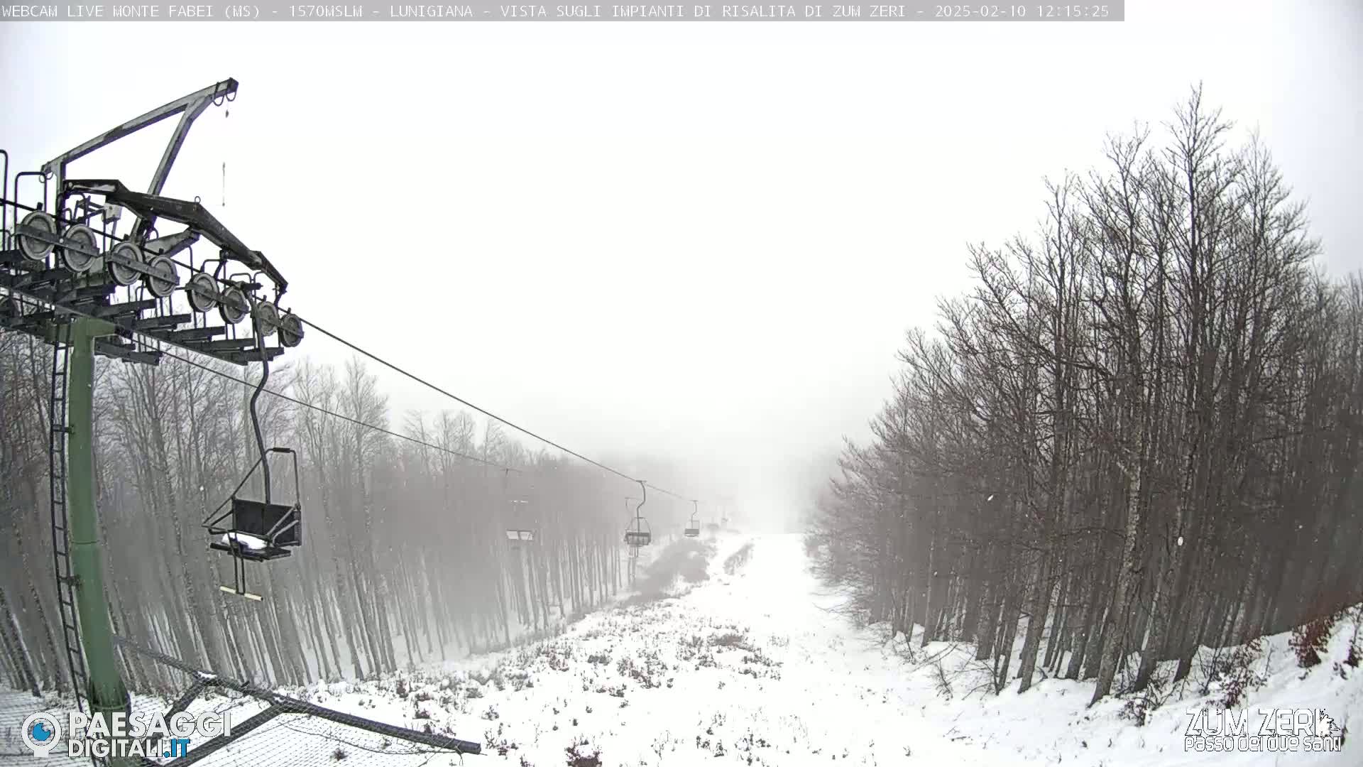 A snow-covered ski lift and slope are visible through falling snow, with bare trees lining the sides.