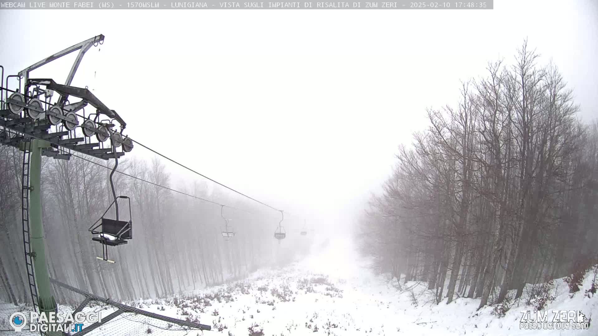 A snow-covered ski lift and trees are visible through a heavy fog.