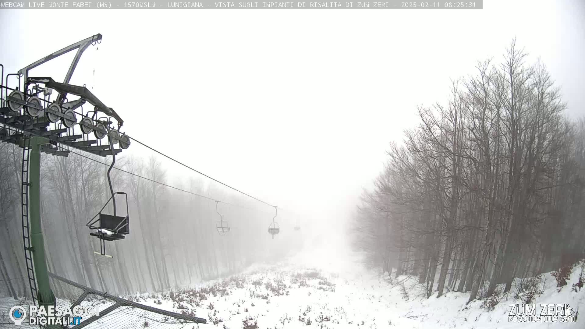 A snow-covered ski lift ascends through a foggy forest.
